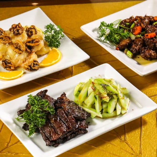 Three white rectangular plates of Asian cuisine, including walnut shrimp, beef, and a vegetable dish.