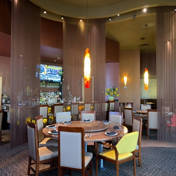 Jazmine restaurant interior with a large round table, chairs, and a bar area in the background.