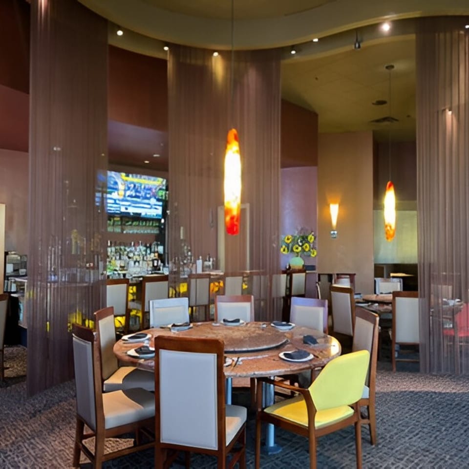 Jazmine restaurant interior with a large round table, chairs, and a bar area in the background.