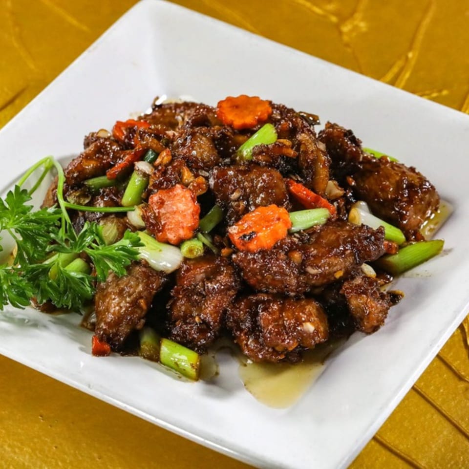 Jazmine's Asian dish features dark glazed meat, green onions, and carrot slices on a white plate.