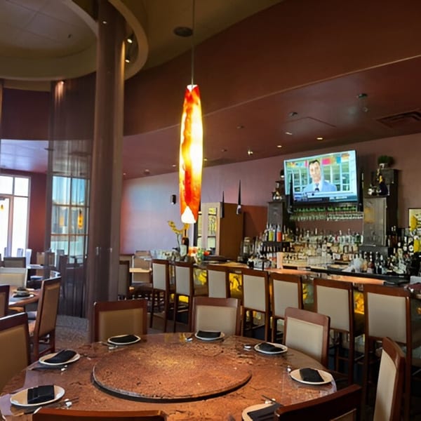 The interior of Jazmine restaurant, featuring a bar with a TV, dining tables, and modern lighting.