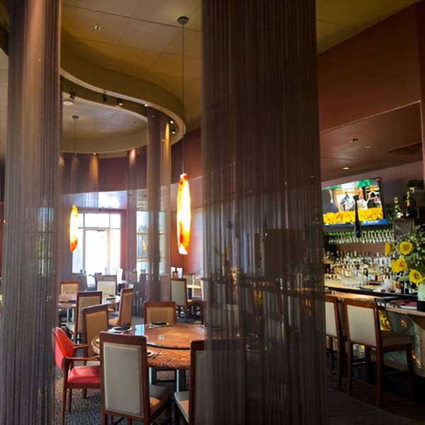 Jazmine restaurant interior with dining tables, a bar, and decorative hanging lights.
