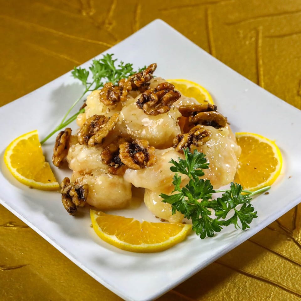 Honey walnut shrimp with orange slices and parsley on a white plate at Jazmine, an Asian restaurant.